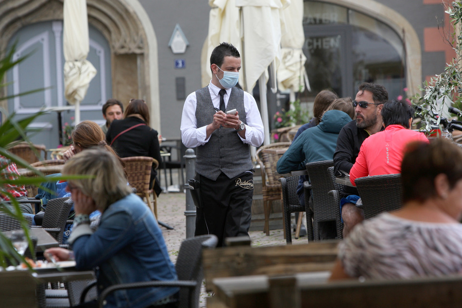 Ein Kellner mit Mundschutz bewirtet die Gäste vor dem italienischen Restaurant La Dolce Vita.