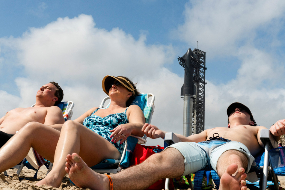A family from Colorado sun bathes as SpaceX's Starship spacecraft is prepared for a third launch.