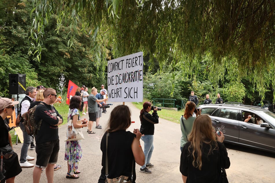 "Compact feiert, die Demokratie wehrt sich" steht auf einem Plakat bei Protesten des Bündnisses für Vielfalt und Demokratie Zeitz gegen das "Compact"-Sommerfest am Rittergut.