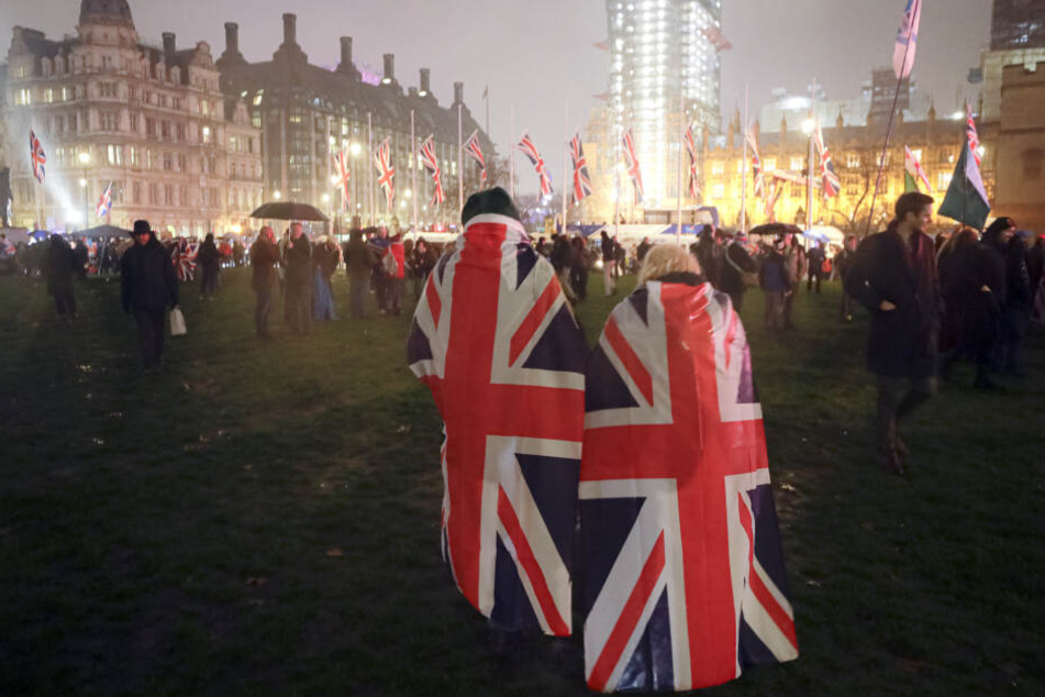 Brexit-Anhänger laufen mit Umhängen, die mit der britischen Nationalflagge bedruckt sind, über den Parliament Square.