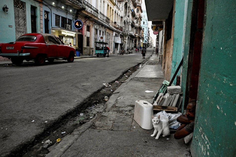 man and his cat sit at the door of their home in Havana, Cuba, on March 13, 2026.