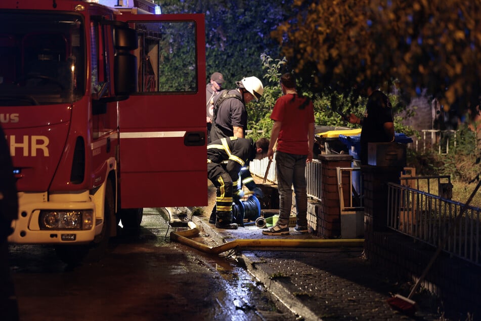 Feuerwehrleute arbeiten mit Pumpen gegen mit Regenwasser voll gelaufene Keller in Erftstadt (NRW).