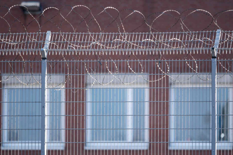 Hinter einem Zaun und Stacheldraht sind Fenster der Justizvollzugsanstalt (JVA) im Stadtteil Ossendorf zu sehen.