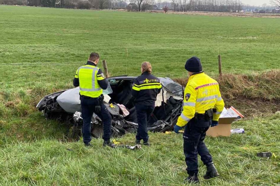 Polizisten untersuchen das Wrack, das am Rande der Autobahn 12 in Richtung Arnheim im Graben liegt.