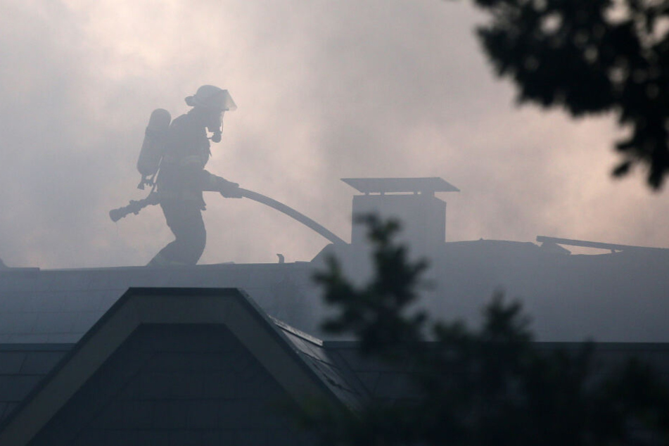 Ein Feuerwehrmann steht auf dem Dach der Anlage und bekämpft den Brand.