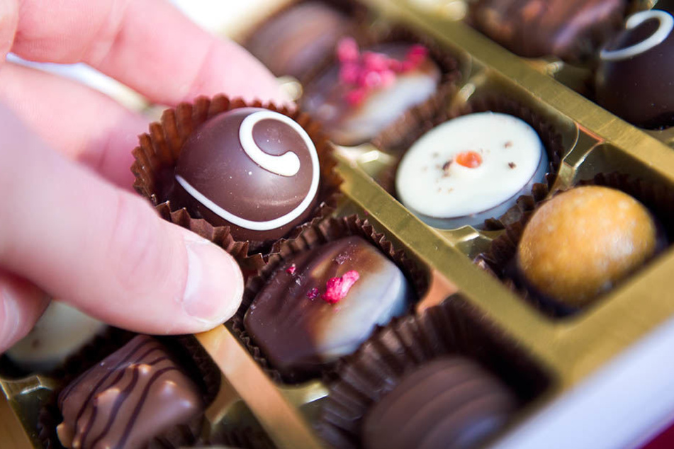Eine Hand greift nach einer Praline in einer Pralinenschachtel. Mehrere Wochen ohne Süßigkeiten zu leben, finden viele Menschen sinnvoll.