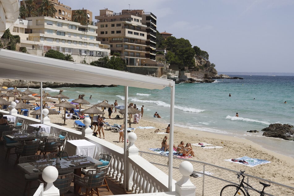 Menschen genießen die Sonne am Strand von Cala Major auf Mallorca. Für deutsche Urlauber gilt nach einem Ausflug auf die Balearen neuerdings Testpflicht.