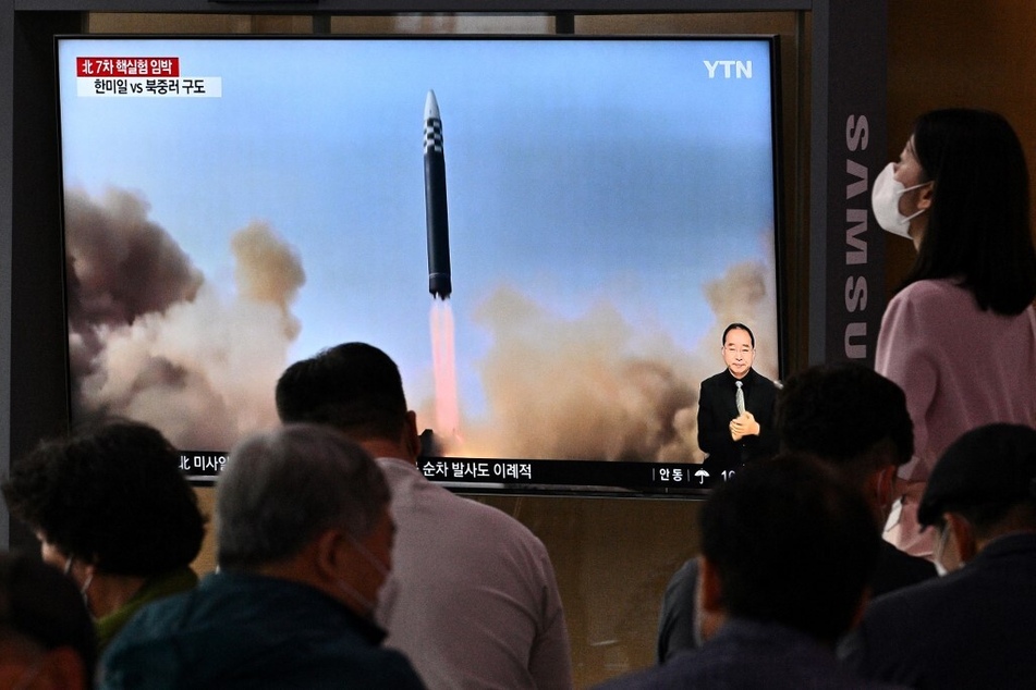 People at a railway station in Seoul sit near a screen on June 5, watching a news broadcast with file footage of a North Korean missile test.