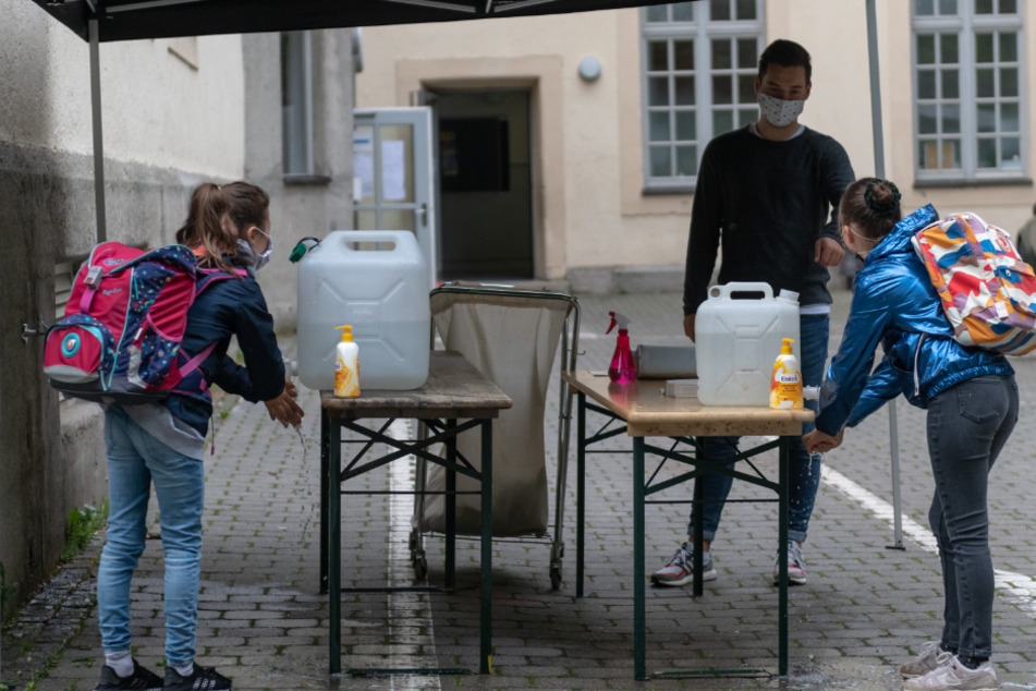 Schülerinnen einer vierten Klasse waschen sich am Morgen im Schulhof unter Aufsicht gründlich die Hände.