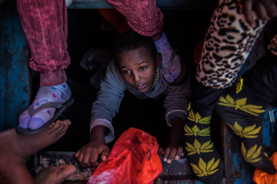 Ein Flüchtlingskind aus Eritrea versucht, an Bord eines überfüllten Holzbootes zu klettern, das auf Hilfe durch das spanische Rettungsschiff von Open Arms wartet.