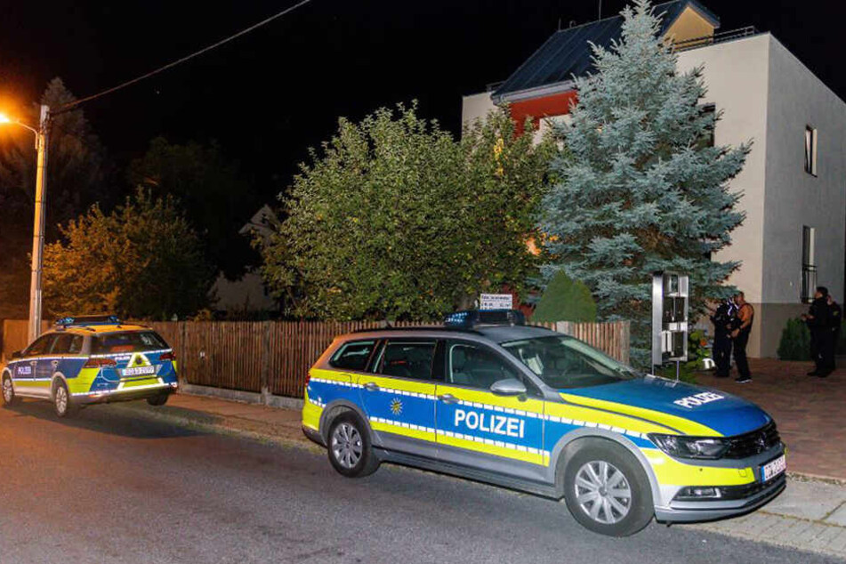 Man sieht die Polizisten, wie sie um das Mehrfamilienhaus postiert sind.