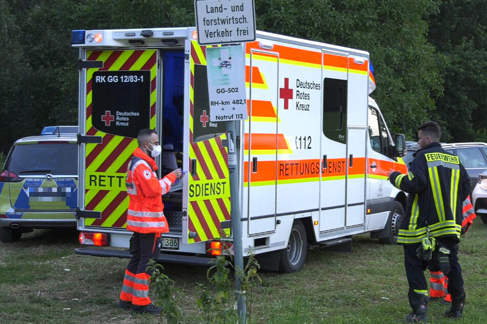 Ein Rettungssanitäter und Feuerwehrmann stehen neben einem Rettungswagen. (Symbolbild)
