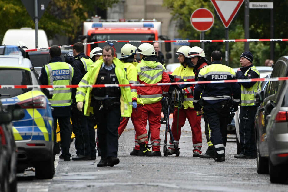 Sanitäter bringen einen Mann zum Krankenwagen der aus einem Fenster gesprungen ist.
