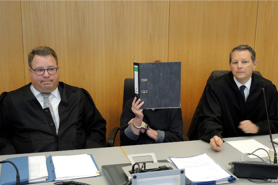 Ulm: Die Angeklagte (M) in einem Prozess wegen Vergewaltigung von zwei demenzkranken Frauen hält sich vor dem Beginn der Verhandlung in einem Saal im Landgericht einen Aktendeckel vor ihr Gesicht.