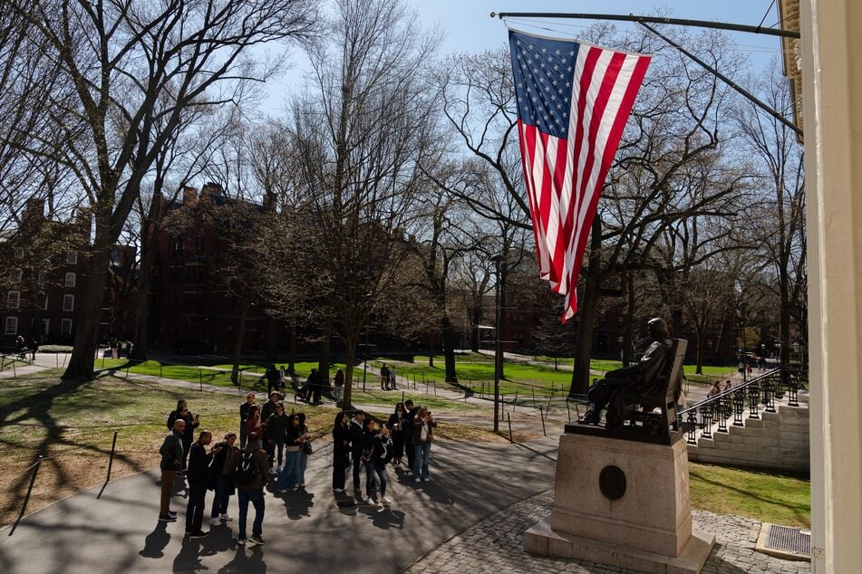 People gather to take photos with the John Harvard Statue at Harvard University on April 17, 2025 in Cambridge, Massachusetts.
