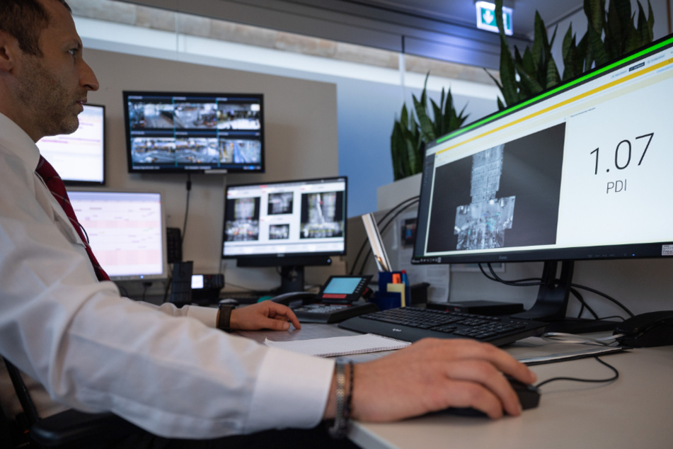 Ein Mitarbeiter sitzt am Flughafen Stuttgart in einem Kontrollraum vor einem Computer, auf dem die Ergebnisse von Überwachungssensoren anzeigt.