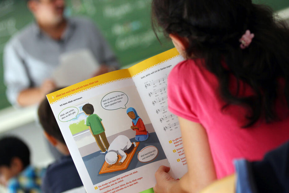 Ein Mädchen liest während des islamischen Religionsunterrichts in einem Schulbuch. (Archivbild)