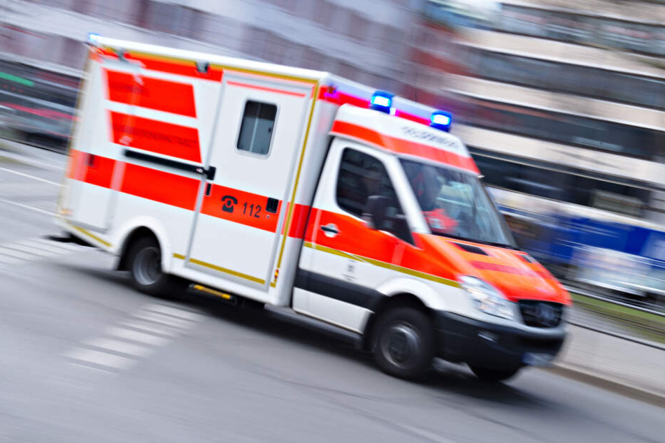 Ein Rettungswagen der Feuerwehr fährt mit Blaulicht durch eine Straße.