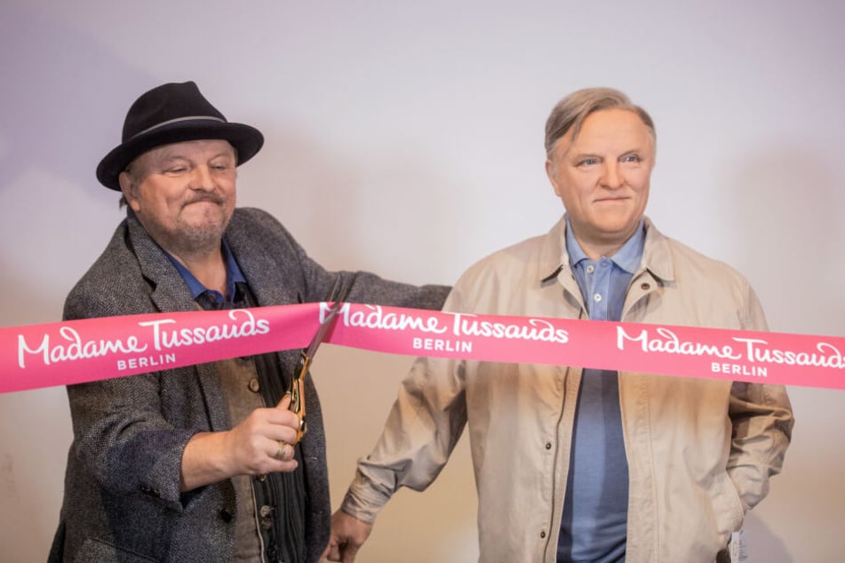 Axel Prahl schneidet ein rotes Band von Madame Tussauds durch.