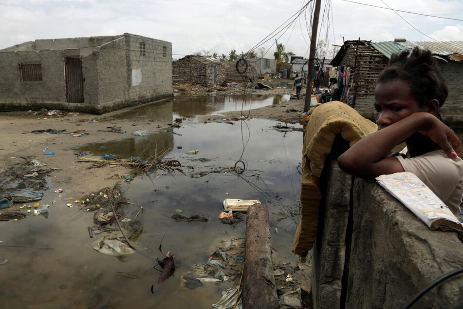 In Beira, Mosambik steht eine Frau nach dem verheerenden Zyklon "Idai" hinter einer Mauer, neben ihr hat sich Wasser in einer Pfütze gesammelt.