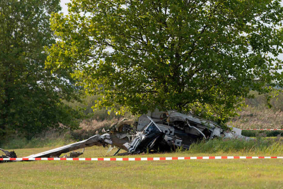 er Wrack eines Kleinflugzeugs liegt nach einem Absturz auf einem Feld zwischen dem Ortsteil Badingen und Gransee hinter einem Absperrband der Polizei.