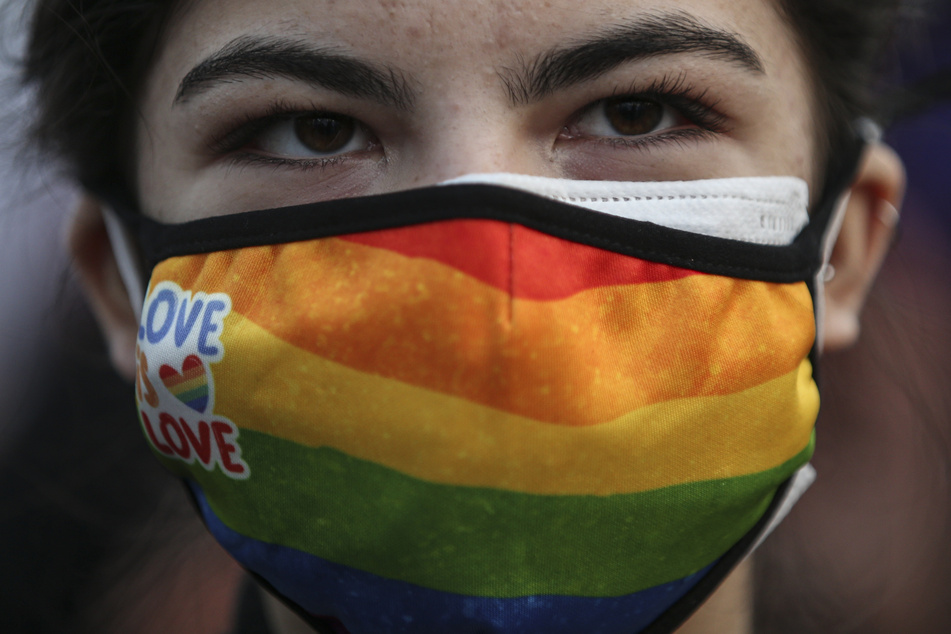 Eine Demonstrantin trägt bei einer Kundgebung gegen Gewalt an Frauen vor dem Internationalen Frauentag einen Mund-Nasen-Schutz in den Farben der Regenbogenflagge.