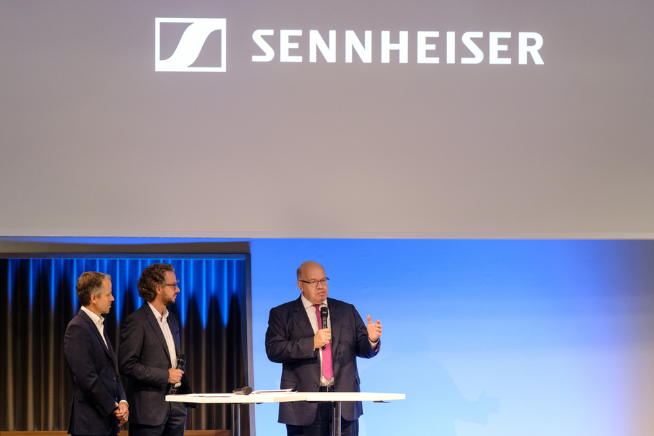 August 2019: Die beiden Geschäftsführenden Gesellschafter des Audio- und Mikrofonherstellers Sennheiser, Andreas Sennheiser (l-r) und Daniel Sennheiser stehen gemeinsam mit Peter Altmaier (CDU), Bundeswirtschaftsminister, beim Unternehmen Sennheiser auf der Bühne.