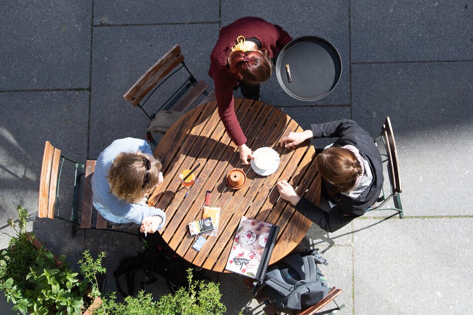 Eine Kellnerin bedient in einem Cafe zwei Frauen.