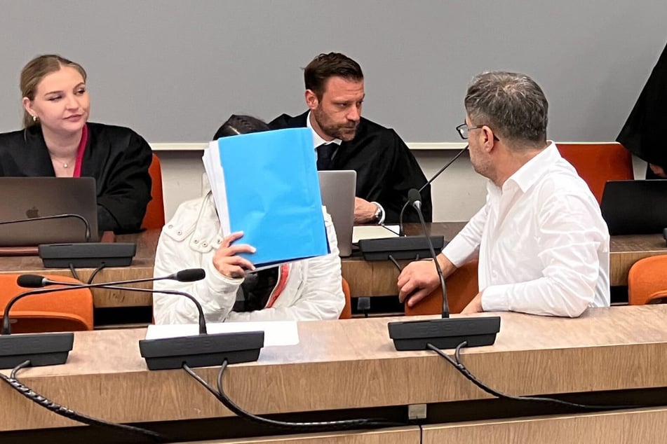 Die wegen Versklavung, Vergewaltigung und Verbrechen gegen die Menschlichkeit angeklagte irakische Frau (2.v.l.) sitzt im Saal des Oberlandesgerichts.