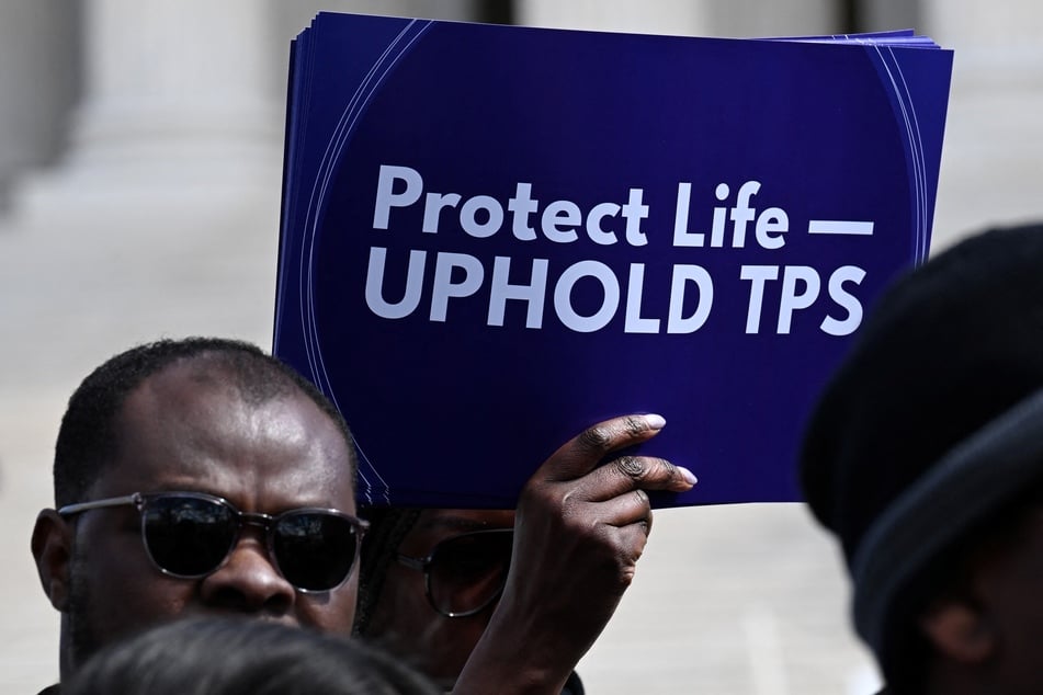 A protester holds a sign calling on the Supreme Court to uphold Temporary Protected Status for Haitians in Washington DC on March 16, 2026.