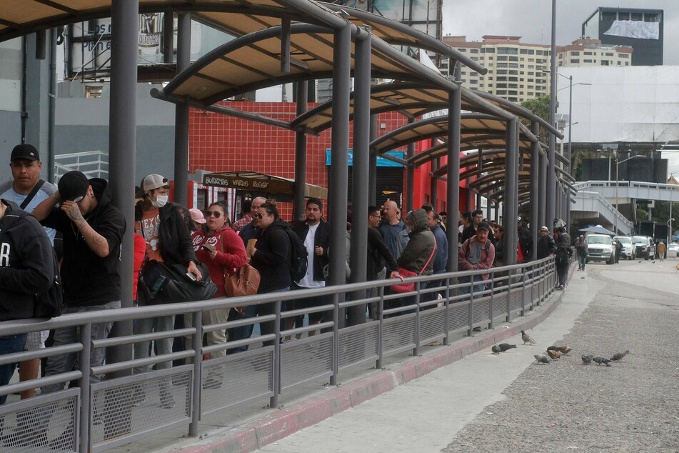 People wait in long lines trying to cross the border to the United States in the city of Tijuana, Mexico.