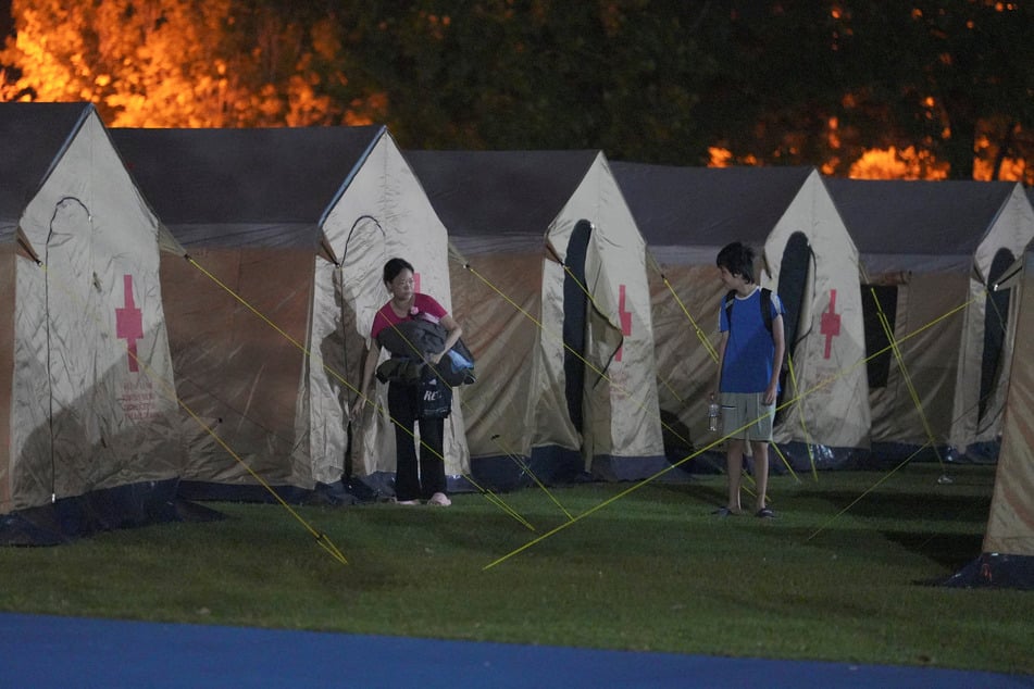 People walk out from tents set up in a school used as a shelter, following an earthquake, in Hualien, Taiwan.