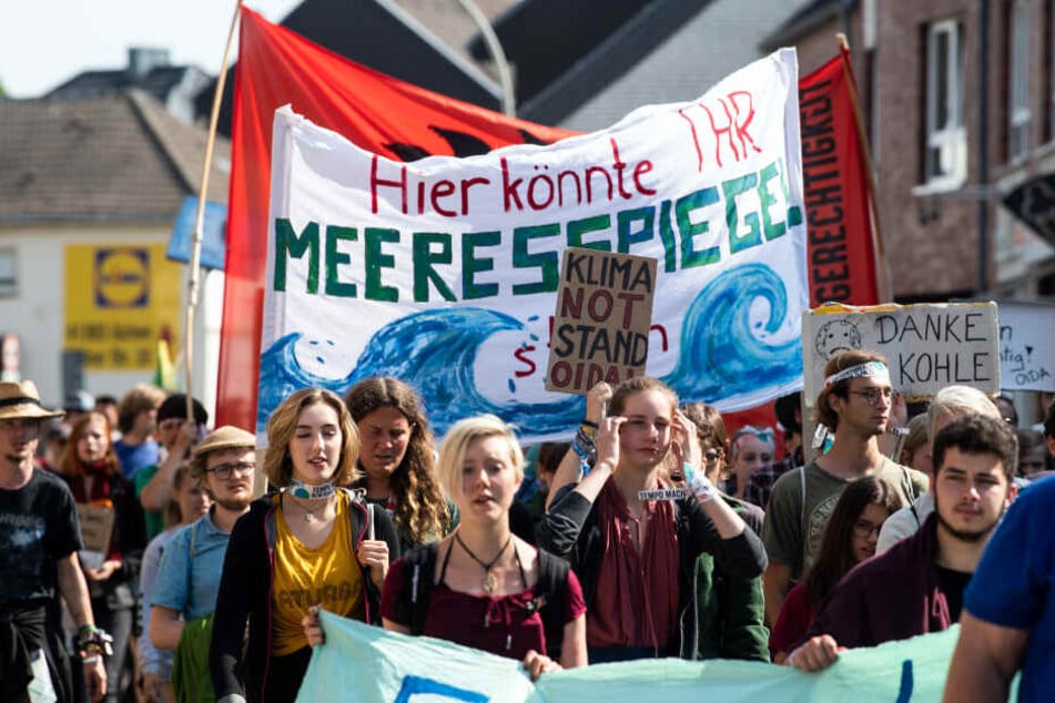 Zahlreiche Demonstranten tragen Banner und Plakate durch Hochneukirch.