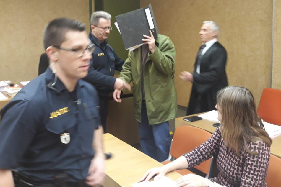 Der Angeklagte (M) wird von Justizbeamten im Amtsgericht in den Verhandlungssaal geführt.