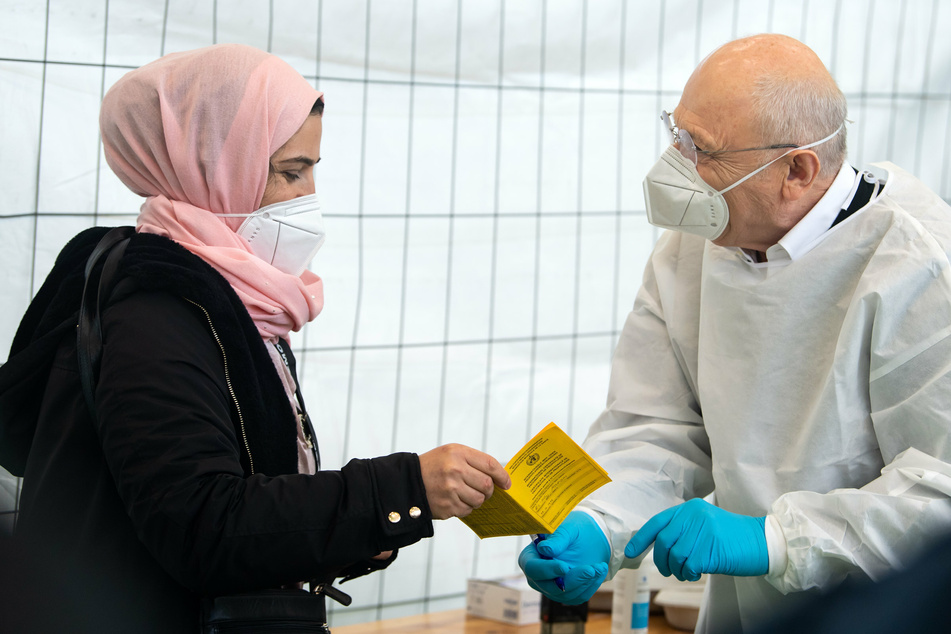 Eine Anwohnerin aus Neukölln lässt sich von Dr. Fatmir Dalladaku in der Turnhalle einer Schule in Neukölln, wo eine Schwerpunktimpfung gegen Corona stattfindet, mit dem Impfstoff von Johnson & Johnson gegen Corona impfen.