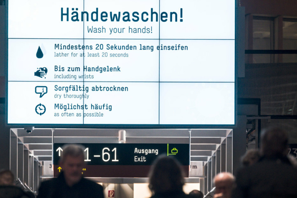 Auf Monitoren sind Tipps zum Schutz vor Infektionen in deutscher und englischer Sprache zu lesen.
