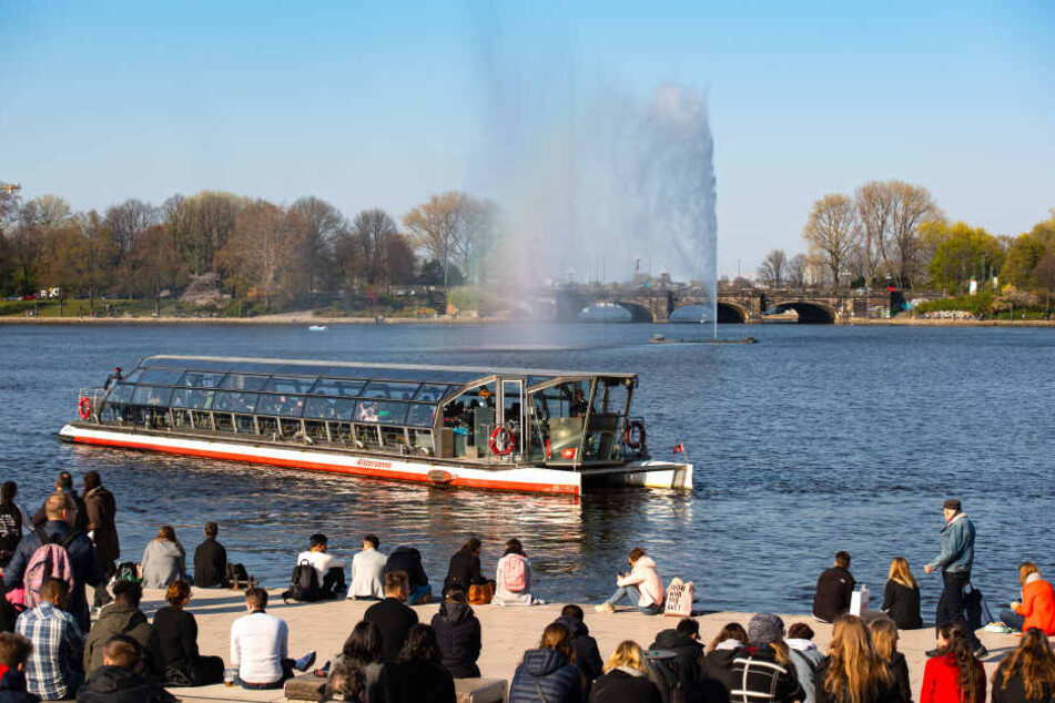 Die Alsterfontäne ist kurz nach ihrer Inbetriebnahme auf der Binnenalster zu sehen, im Vordergrund legt eine Barkasse am Jungfernstieg an.