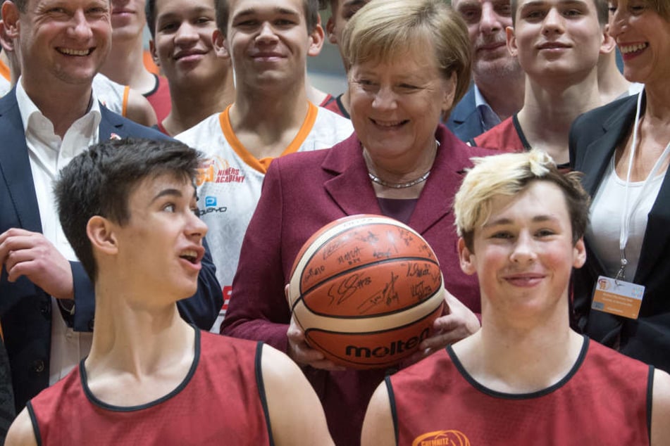 Micaela Schönherr (r.), Präsidentin des Basketball-Zweitligisten Niners Chemnitz, Bundeskanzlerin Angela Merkel (CDU) und Steffen Herold, Geschäftsführer der Niners, unterhalten sich beim Training des Nachwuchsteams des Basketball-Vereins in Chemnitz mit