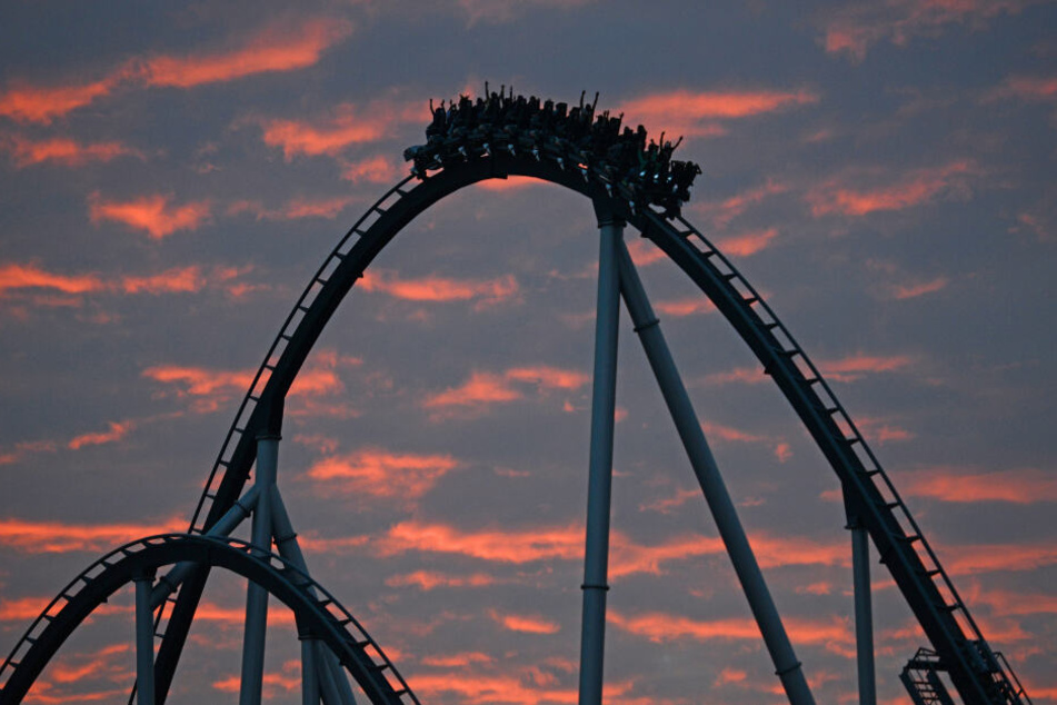Eine Achterbahn fährt im Sonnenuntergang.