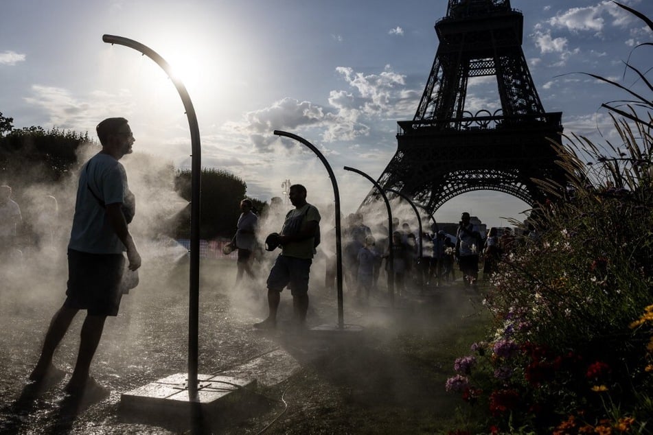 People cool off with water sprays near the Eiffel Tower during the Paris Olympics.