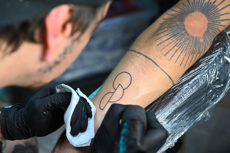 Das Tattoo besteht aus einem Kreis und zwei Halbkreisen, die ineinander verbunden sind.