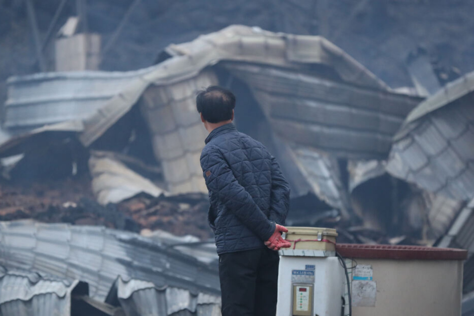 Ein Mann betrachtet in Südkorea ein völlig ausgebranntes Haus.