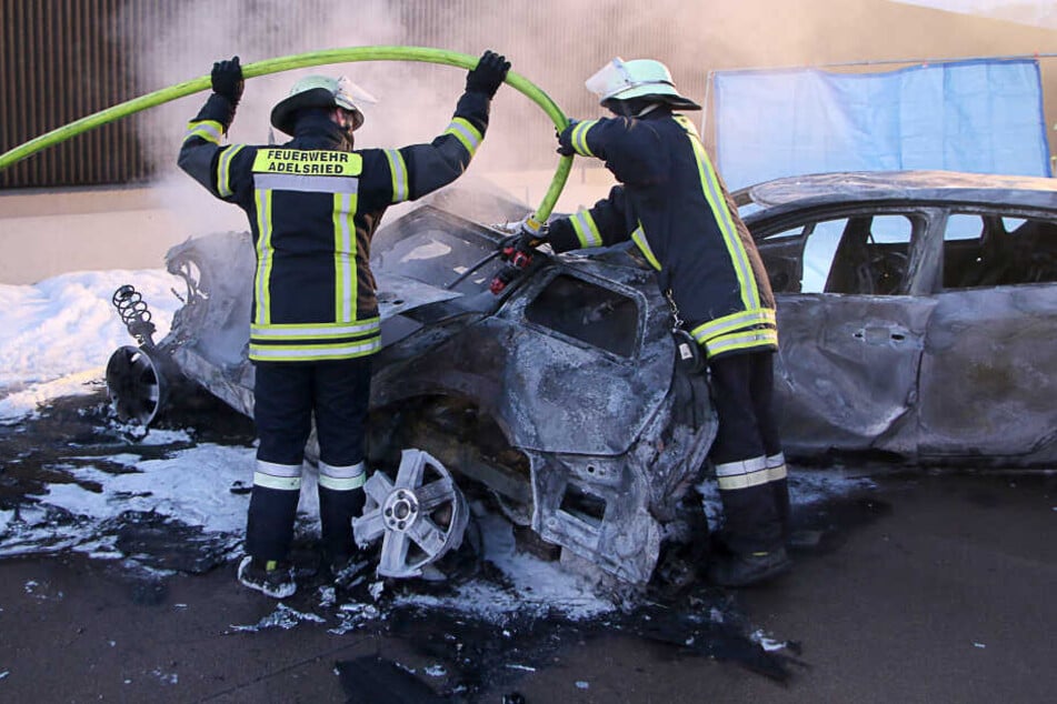 Feuerwehrmänner sind an einer Unfallstelle auf der Autobahn A8 mit Nachlöscharbeiten beschäftigt.