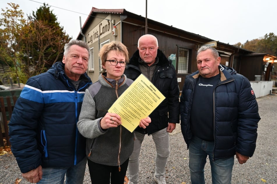 Pächterin Kathrin Pege (50) zeigt den Informationsaushang zur Schließung des Gartenlokals "Lug ins Land". Die Stammgäste Volker Straube (65, v. l.), Frank Groschupp (69) und Siegmund Frank (64) sind frustriert.