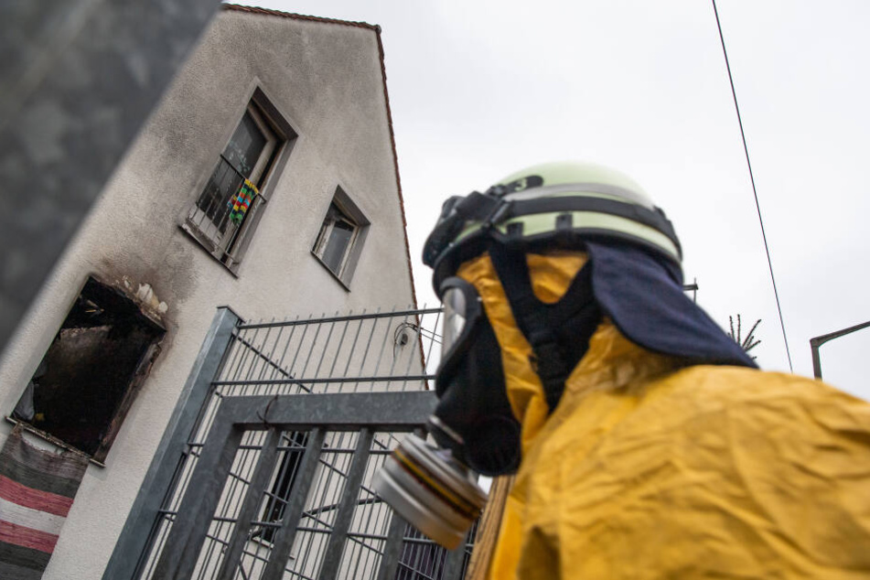 Ein Feuerwehrmann in Atemschutzkleidung vor dem ausgebrannten Haus in Nürnberg.