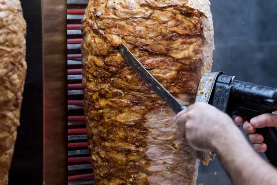 Von einem Dönerspieß wird Fleisch abgeschnitten.