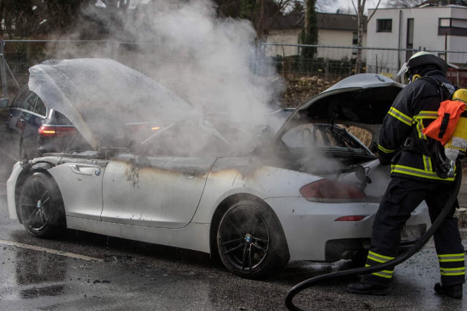Ein Feuerwehrmann löscht den Brand im Sportwagen.