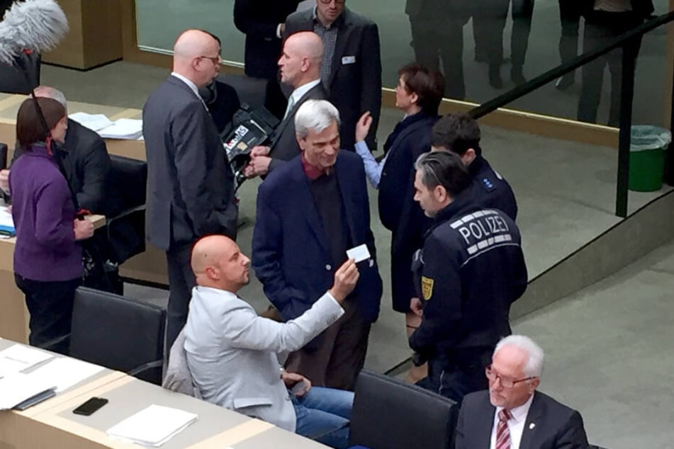 Stefan Räpple (sitzend, l.), Abgeordneter der AfD im Landtag von Baden-Württemberg und der fraktionslose AfD-Politiker Wolfgang Gedeon (Mitte) sprechen während einer Plenarsitzung mit Polizisten.