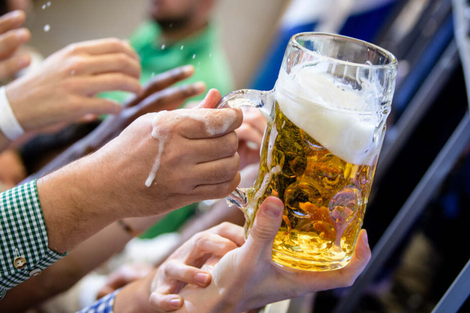 Besucher greifen im Paulaner-Festzelt nach einem Bierkrug.