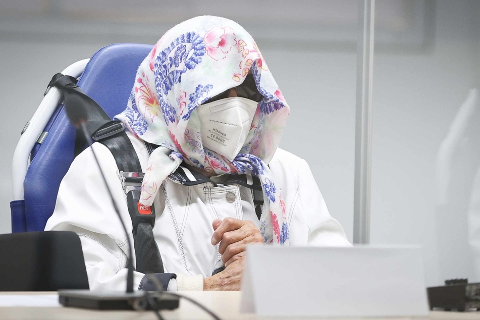 Die 96-jährige Angeklagte Irmgard F. sitzt in einem Krankentransportstuhl hinter einer Plexiglasscheibe im Gerichtssaal.